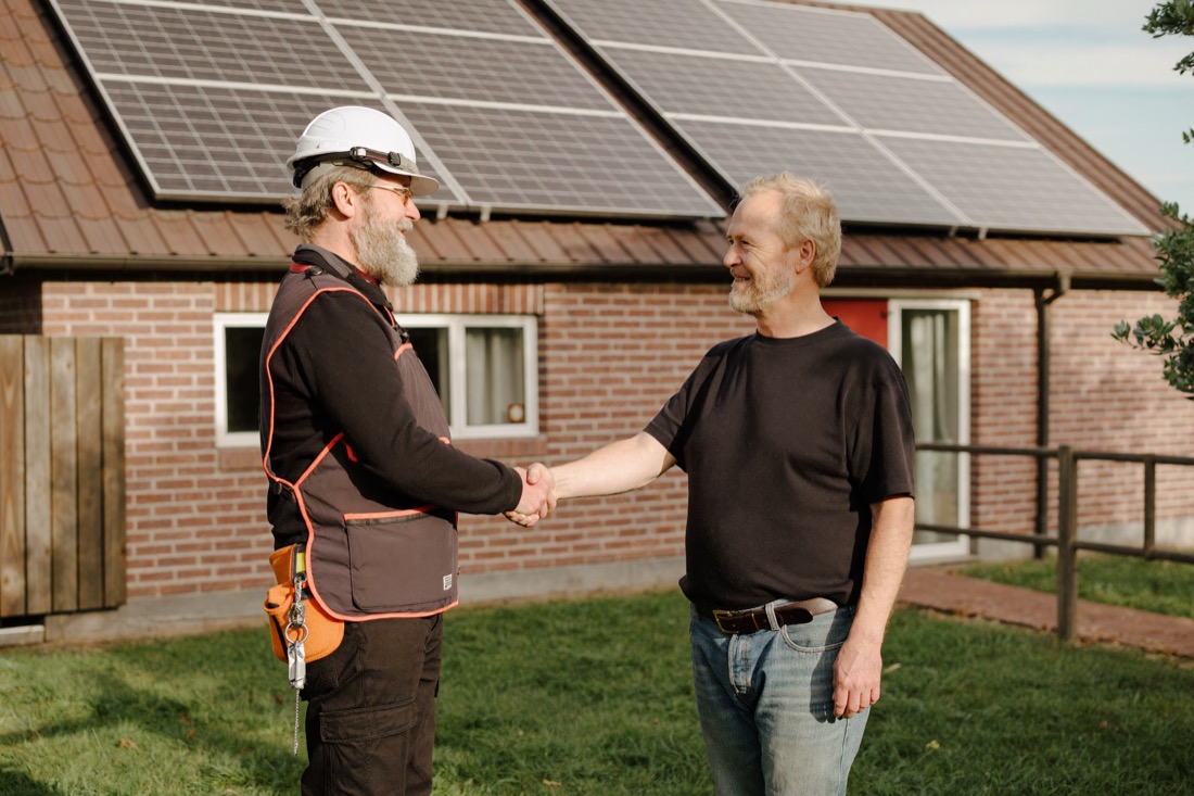 Onze monteur schudt de hand van een klant voor diens woning met zonnepanelen